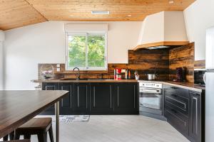 eine Küche mit schwarzen Schränken und einer Holzdecke in der Unterkunft Gîte Panda in Marans