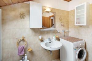 a bathroom with a sink and a washing machine at Mansarda Maema in Moena