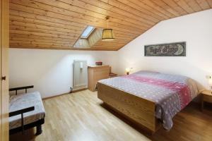 a bedroom with a bed and a wooden ceiling at Mansarda Maema in Moena