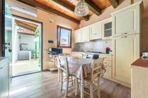 a kitchen with white cabinets and a table and chairs at Da Giò, a due passi dal mare in Calasetta