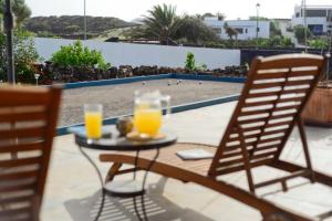 two glasses of orange juice on a table with two chairs at Casa Jenabe in La Vegueta +21 photos