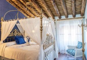 a bedroom with a canopy bed and a chair at Casa Rural El Baluarte Habitaciones in Noves