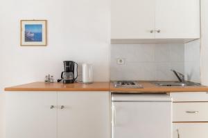 a kitchen with white cabinets and a wooden counter top at Sifnos studio 5 in Sifnos