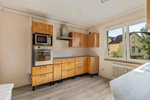 a kitchen with wooden cabinets and a microwave at Aparthotel am Stadtpark in Bad Sachsa
