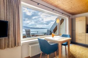 a room with a table and chairs and a large window at Merk Ferienwohnungen Gbr in Bodman-Ludwigshafen