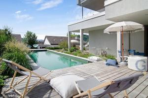 a deck with chairs and an umbrella next to a swimming pool at Seeart-apartment No 86 in Ludwigshafen