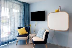 a room with a mirror and two chairs and a tv at Seeart-apartment No 86 in Ludwigshafen