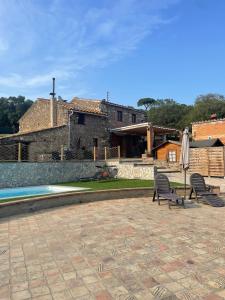 a patio with two chairs and an umbrella next to a pool at Masia Can Vilar in Maçanet de la Selva