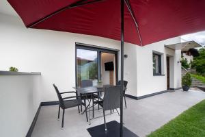a patio with a table and chairs under a red umbrella at Haus Nummer 9 in Marlengo