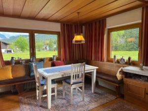 a dining room with a table and chairs and windows at Birkenhof in Leutasch