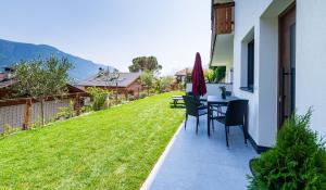 a patio with a table and chairs and a lawn at Haus Nummer 9 in Marlengo