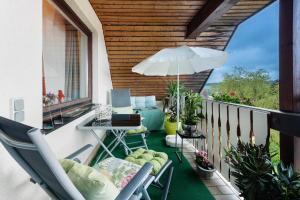 a balcony with chairs and a table and an umbrella at Appartement am Kirnbergsee in Bräunlingen