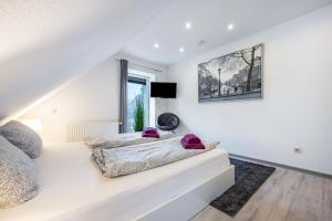 a bedroom with white walls and a bed with purple pillows at To Huus am Steinhuder Meer in Steinhude