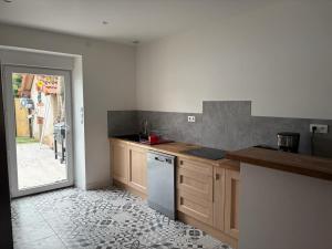 a kitchen with wooden cabinets and a white dishwasher at Maison de vacances avec piscine in Messeix