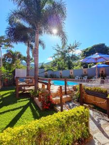 a resort with a swimming pool and palm trees at Pousada Flor De Lótus Cipó in Serra do Cipo
