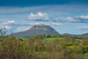a mountain in the middle of a field with trees at Maison de vacances avec piscine in Messeix