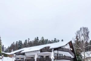 a building covered in snow with trees in the background at Köhlerstube Todtmoos in Todtmoos