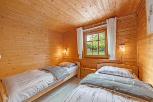 zwei Betten in einer Blockhütte mit Fenster in der Unterkunft Moi Holzhaisel in Elmstein