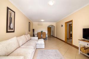 a living room with a white couch and a tv at O'pomar 150 in Tavira