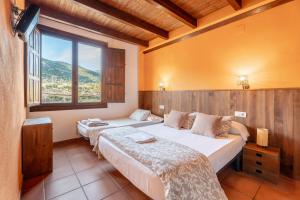two beds in a room with a large window at La Posada in Chera