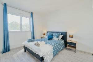 a bedroom with a blue and white bed and a window at Maison avec jardin proche Dinan in Trévron