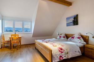 a bedroom with a bed and a table and two windows at Pension Zum Talhof in Reichenau