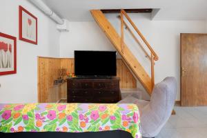a living room with a couch and a tv and a staircase at Casa della Rosina in Bresimo