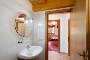 a bathroom with a sink and a mirror and a bedroom at Appartamenti Camilla in Canazei +50 photos