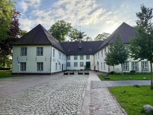 a large white building with a cobblestone driveway at Ferienhaus Neeborg in Zetel