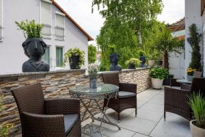 a patio with a table and chairs and a stone wall at Ferienwohnungen Eulenspiegel in Breisach am Rhein