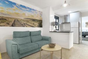 a living room with a blue couch and a kitchen at Apartamentos Bellamar in Barbate