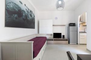 a white room with a bed and a refrigerator at La Pelusa Peschiera in Peschiera del Garda