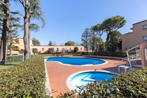 two swimming pools in a yard with trees and a building at La Pelusa Peschiera in Peschiera del Garda