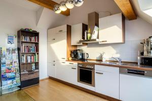 a kitchen with white cabinets and a book shelf at Pension Zum Talhof in Reichenau