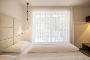 a bedroom with a white bed and a window at Apartment Treï Residence Bun Ste in San Vigilio Di Marebbe