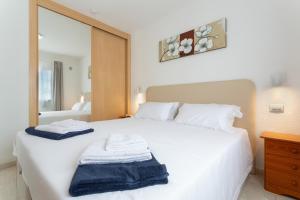 a bedroom with a white bed with towels on it at La Casita Encantada in Corralejo +20 photos