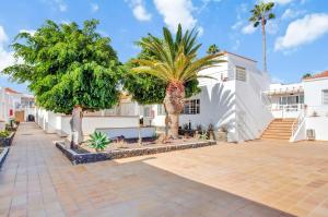 a courtyard with palm trees and a white building at La Casita Encantada in Corralejo