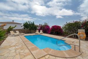 a swimming pool with chairs and flowers in a yard at La Tunera in La Cisnera