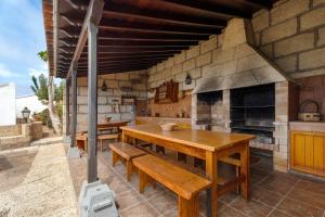 a kitchen with a wooden table and a fireplace at La Tunera in La Cisnera