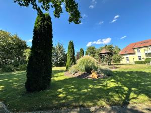 a dog laying in the grass in a yard with a gazebo at Herrenhaus Carolinenhof in Groß Plasten