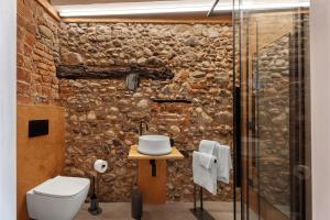 a bathroom with a stone wall with a toilet and a sink at Decanter House in Borgomanero +41 photos