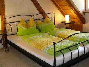a bed with green and yellow pillows on it at Alte Wassermühle in Salem