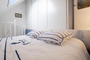 a white bed with two pillows on top of it at Appartement Guillaume vue mer in Trégunc