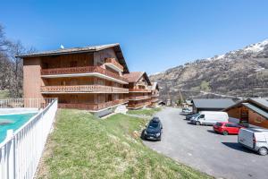 a building with cars parked next to a parking lot at Les arolles in Valloire