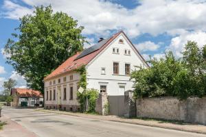 a white house with a red roof on a street at Ferienwohnung mit großem Garten in Lindow