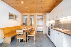 a kitchen with white cabinets and a wooden ceiling at Seppnerhof Ferienwohnung Enzian in Moso +13 photos
