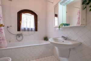 a white bathroom with a sink and a bath tub and a sink at Trilocale Fiordaliso in Stintino +15 photos