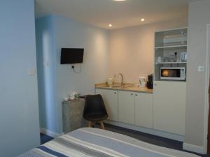 a bedroom with a bed and a kitchen with a sink at The Florian in Weymouth