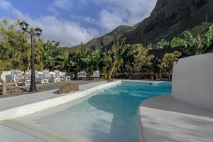 a swimming pool with chairs and a mountain in the background at Finca Oasis Samuel in Garachico