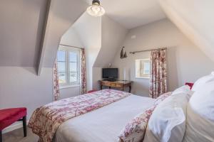 a bedroom with a bed and a tv and a window at Hôtel de la Pointe du Grouin in Cancale